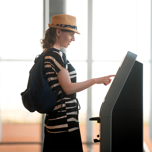 Woman checking in on her own at the hotel self-service kiosk of Clock Software